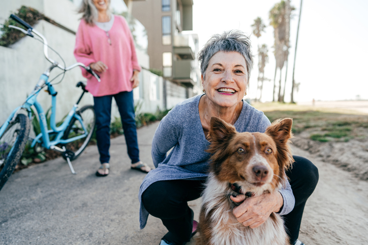 Smiling woman crouching beside her dog next to a pair of bicycles