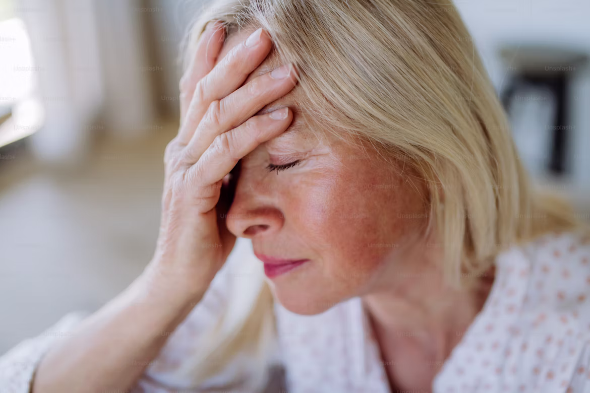 Sad older woman sitting down with her hand holding her head