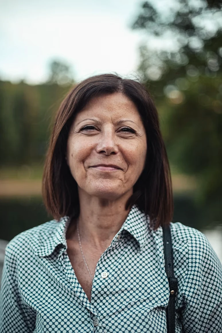 Middle-aged woman in a blue- and white-collar shirt smiling
