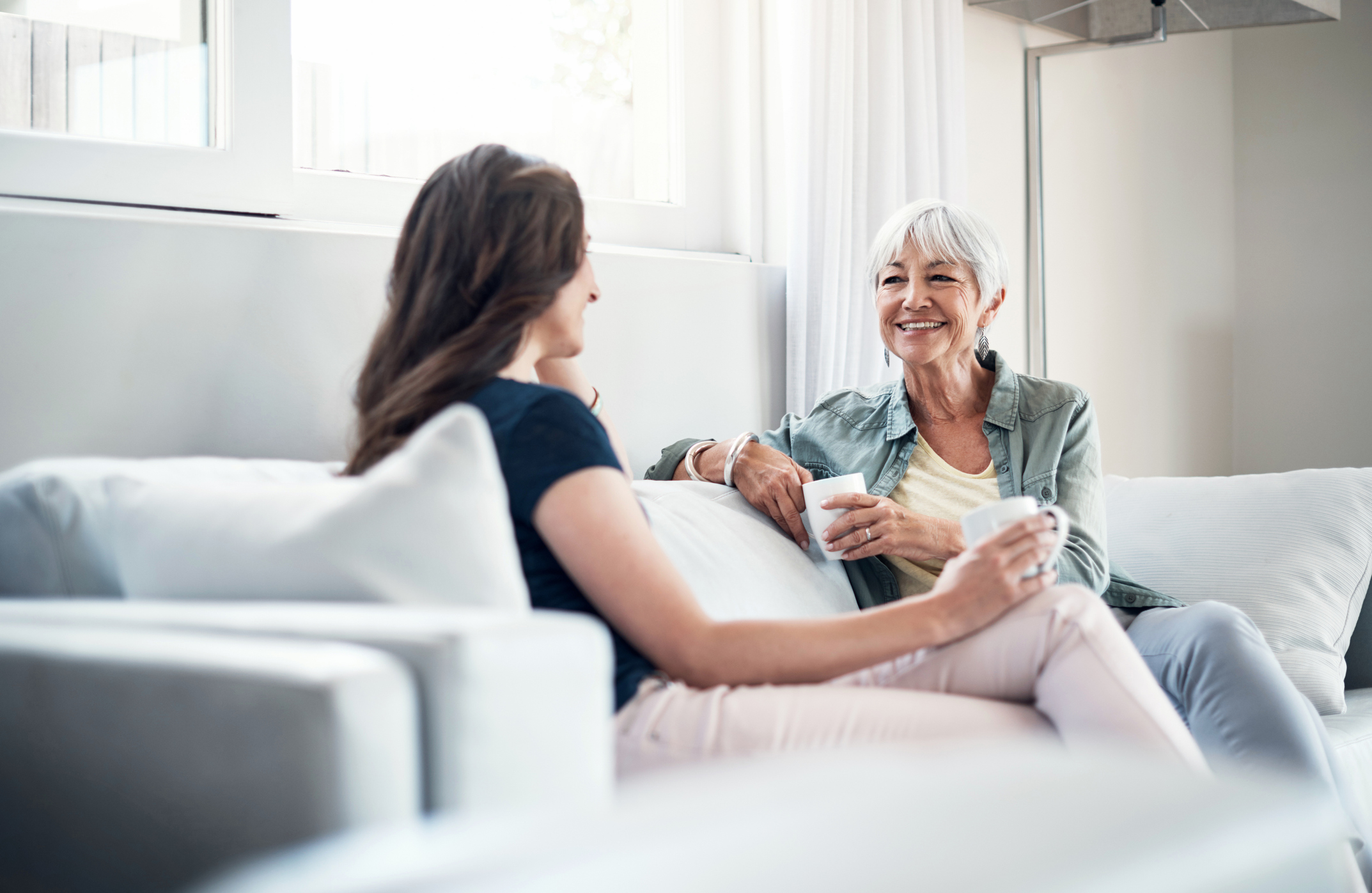 Two women talking over coffee on a couch